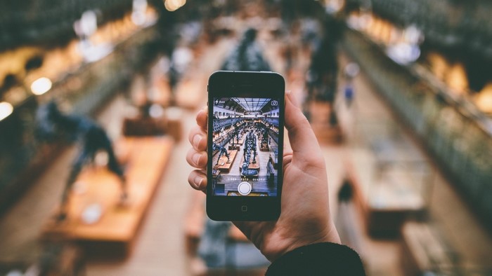 Person holding a smartphone taking a picture of a museum exhibit