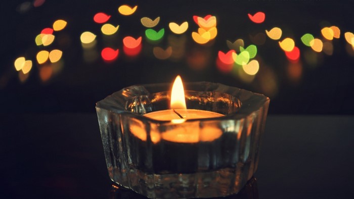 Candle flame in a glass holder with bokeh lights