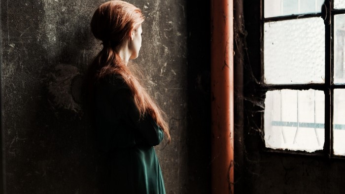 Woman with red hair looking out a window