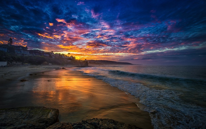 Sunset over a beach with colorful clouds and ocean waves
