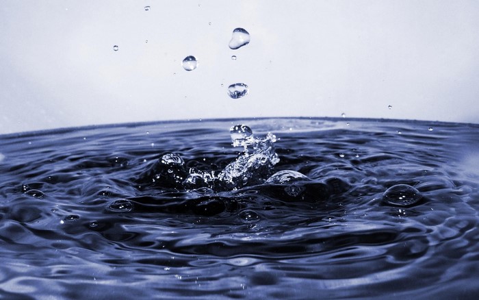 Water splash and drops in dark blue water