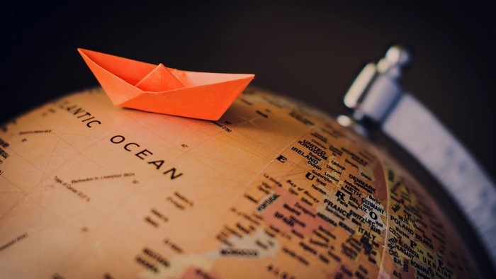 Orange paper boat on a globe