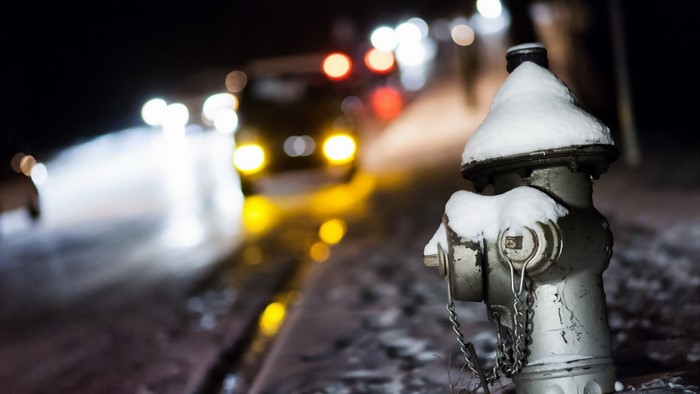 Snow-covered fire hydrant at night with bokeh lights