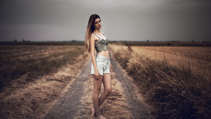 Woman in crop top and denim shorts on a dirt road