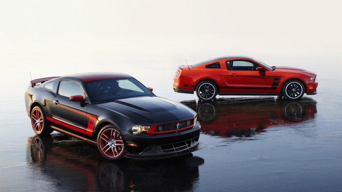 Two Ford Mustang Boss 302 cars on wet surface