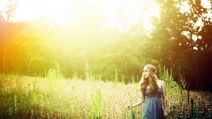 Woman in a blue dress in a sunlit field