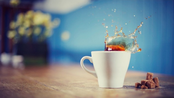 Coffee splash in a white cup with sugar cubes