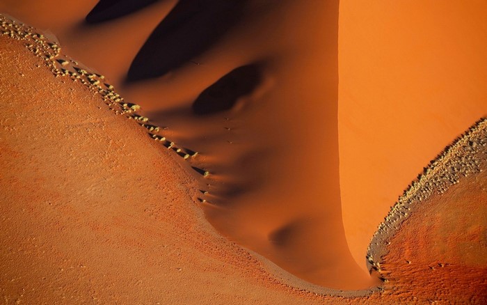 Aerial view of red sand dunes with sparse vegetation