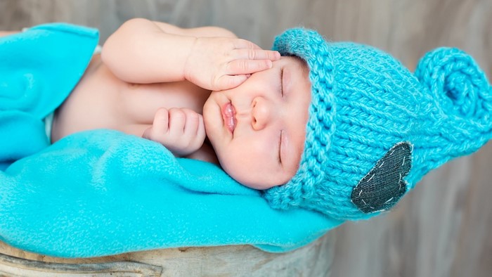 Baby wearing a blue knitted hat and blanket