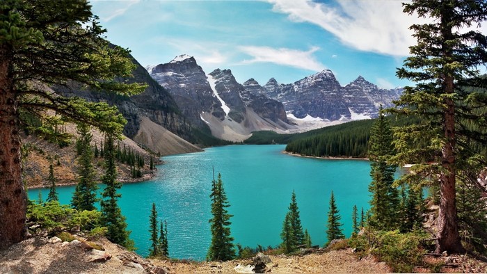 Turquoise lake surrounded by pine trees and snow-capped mountains