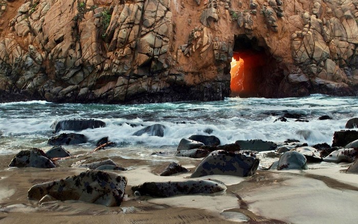 Cave entrance in a rocky coast with waves crashing