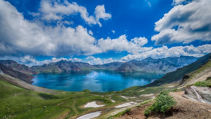 Crater lake surrounded by mountains under a cloudy sky