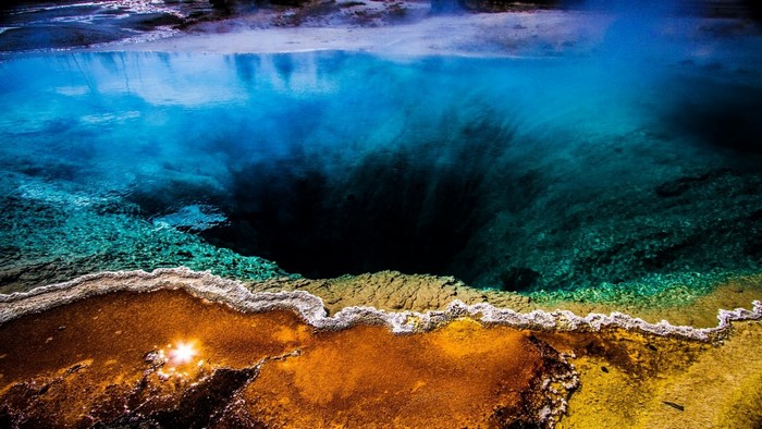 Deep blue geothermal pool with colorful mineral deposits