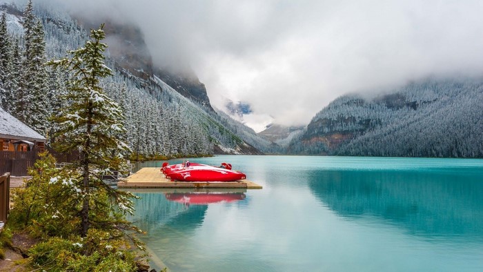 Red canoes on a dock in a snowy mountain lake