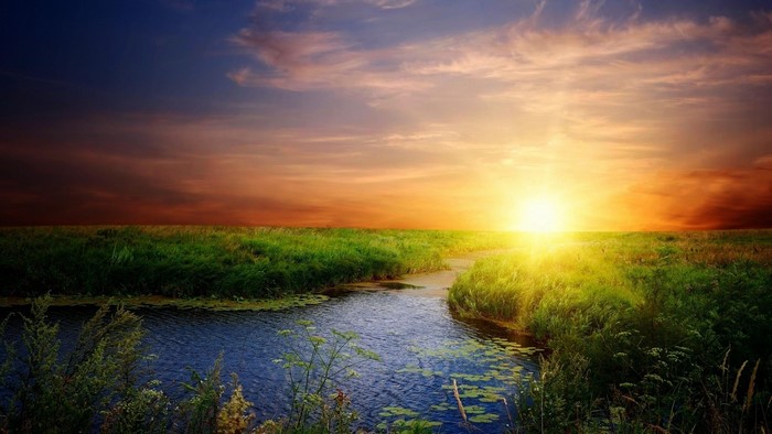 Sunset over a river and grassy field