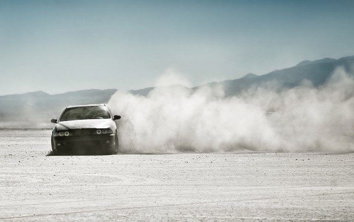 Car drifting in dust cloud in desert landscape