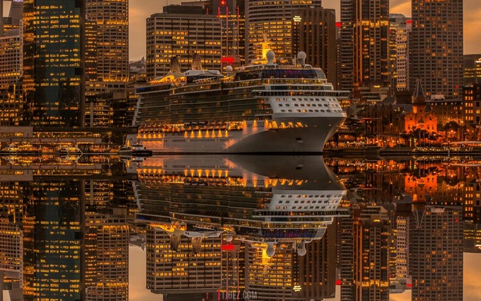 Cruise ship docked in Sydney harbor at dusk with city skyline reflection