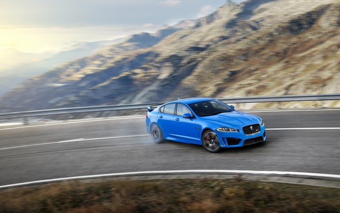 Blue Jaguar sports car drifting on a mountain road
