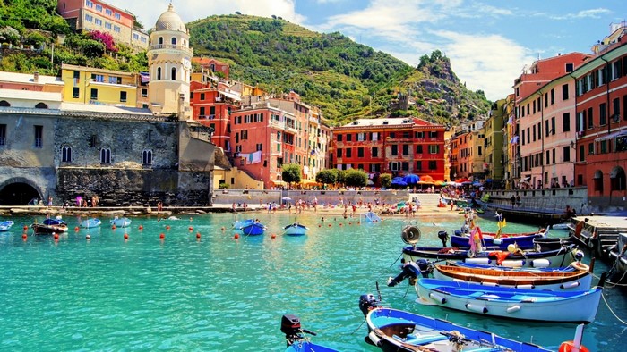 Colorful village on a hill overlooking a turquoise bay with boats