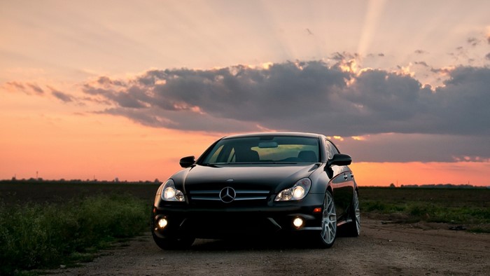 Black Mercedes-Benz CLS parked on a dirt road at sunset