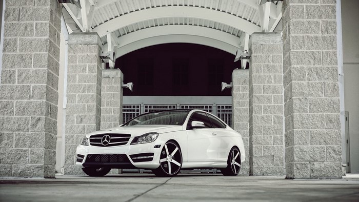 White Mercedes-Benz Coupe parked under stone archway