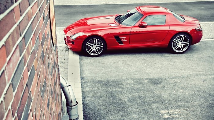 Red Mercedes Benz SLS AMG parked next to a brick wall