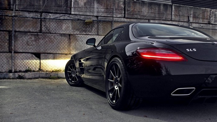 Black Mercedes-Benz SLS AMG coupe parked near a concrete wall