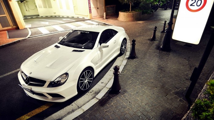 White Mercedes-Benz AMG SL sports car parked on cobblestone street
