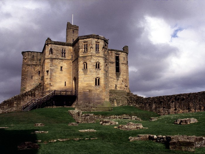 Castle ruins on a grassy hill under a cloudy sky
