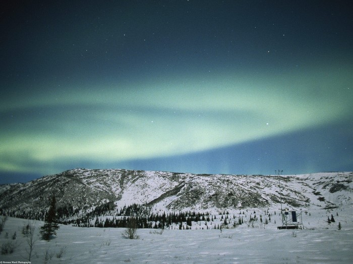 Aurora Borealis over a Snowy Mountain Landscape