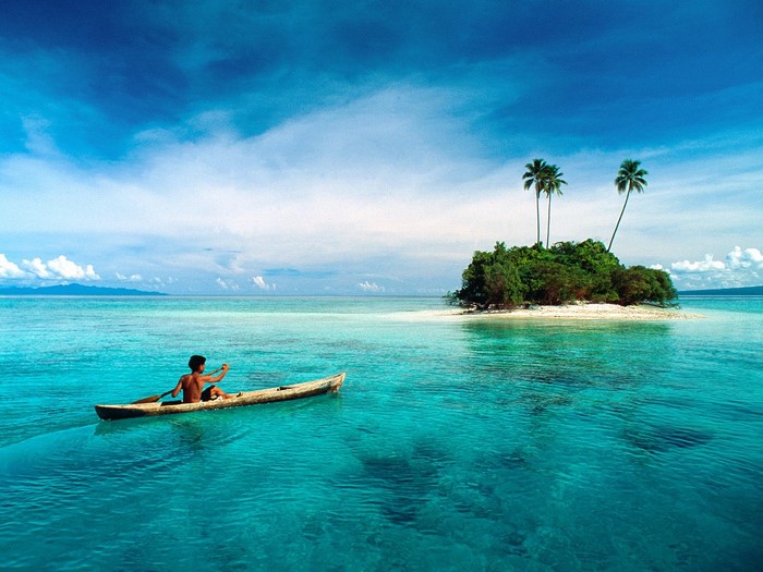 Man paddling canoe towards tropical island