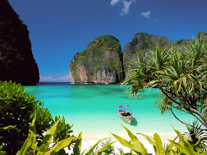 Tropical island bay with limestone cliffs and a longtail boat