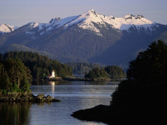 Lighthouse on an island with snow-capped mountains