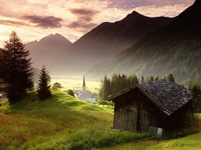 Alpine valley with church and cabin at sunrise