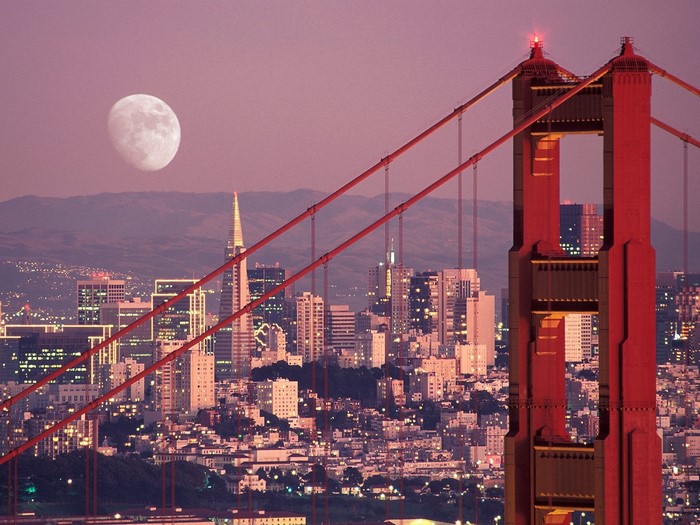 Golden Gate Bridge tower with San Francisco skyline and moon