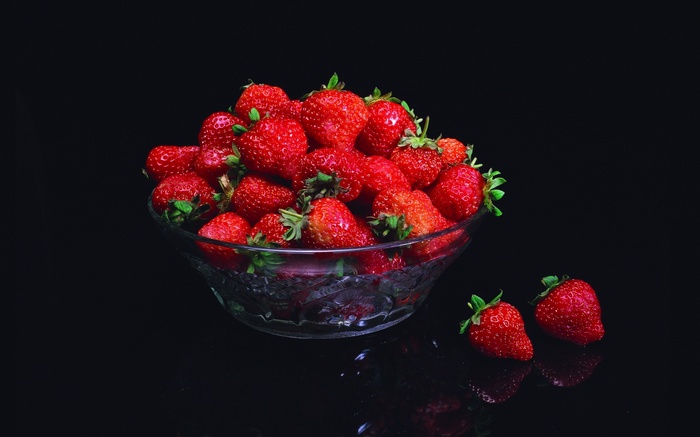 Bowl of strawberries with two strawberries on the side
