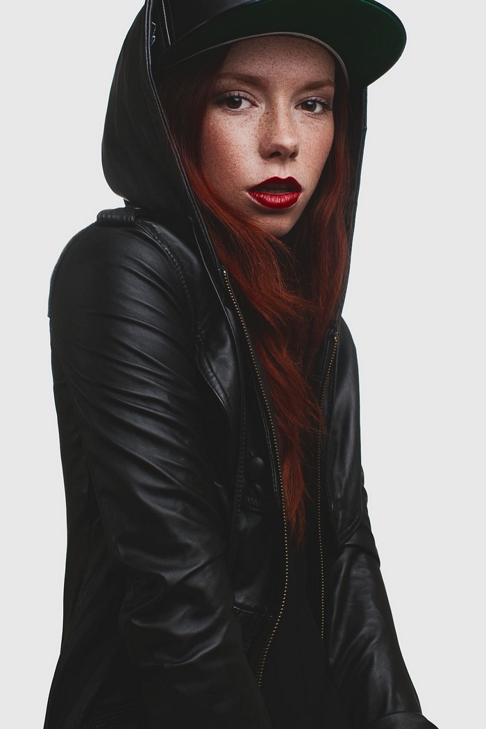 Woman with red hair wearing a black leather jacket and cap