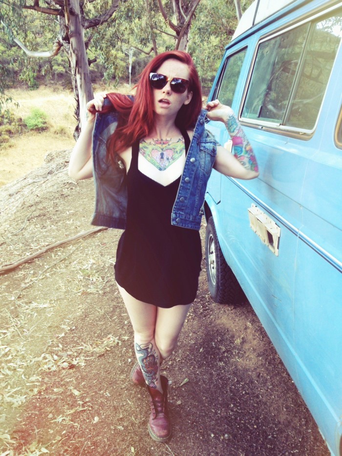 Woman with tattoos and red hair by a blue van