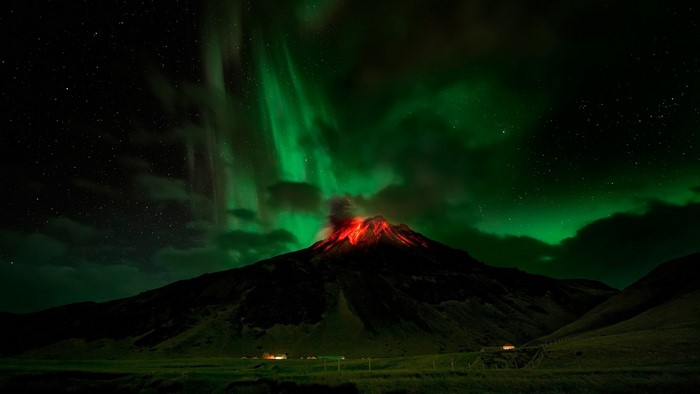 Volcano erupting under Aurora Borealis at night