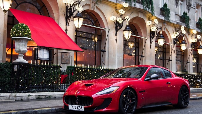 Red Maserati GranTurismo parked in front of a building with a red awning