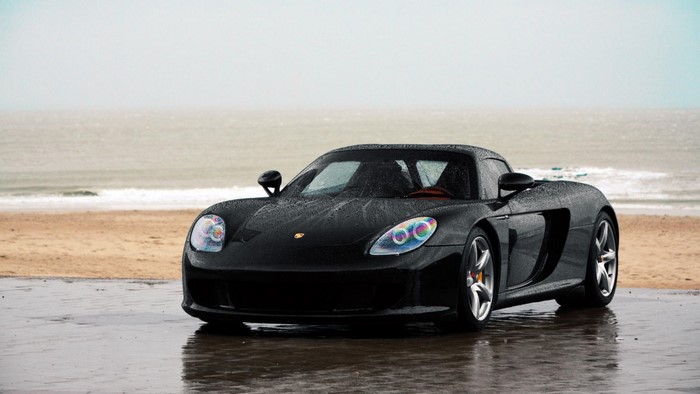 Black Porsche Carrera GT on a wet beach