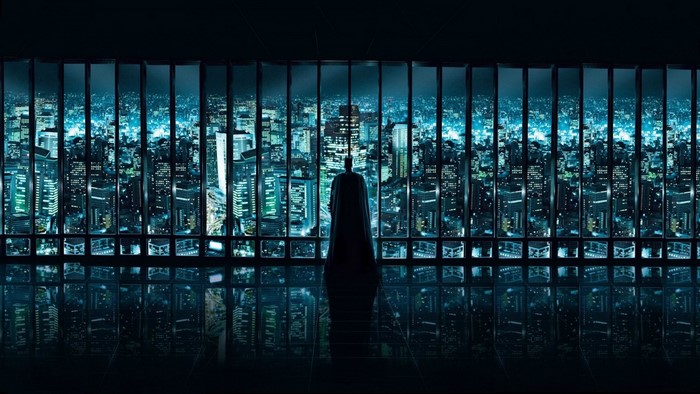 Batman overlooking a futuristic cityscape at night