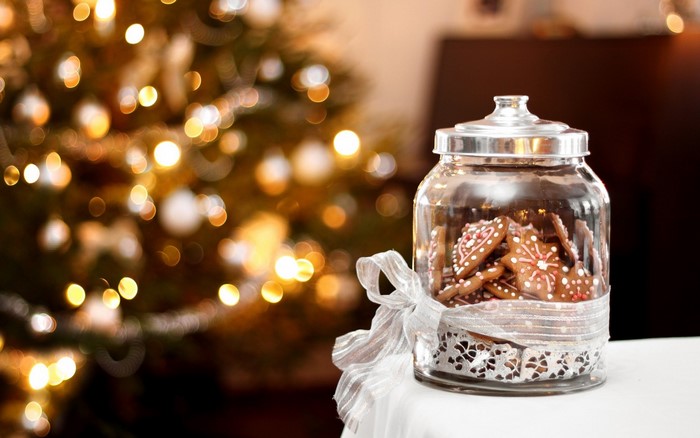Jar of Christmas cookies with ribbon and Christmas tree bokeh
