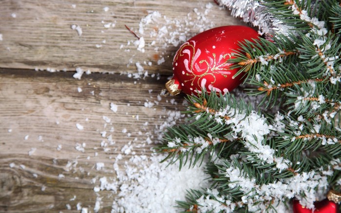 Christmas ornament on a snowy fir branch on wood