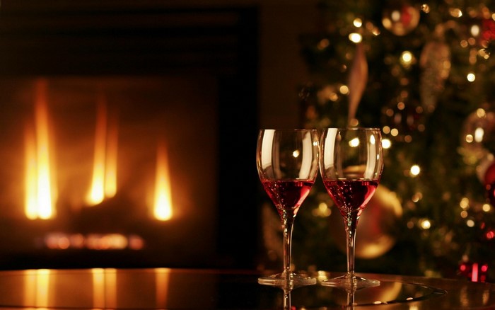 Two wine glasses by a fireplace and Christmas tree