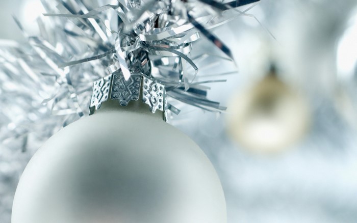 Close-up of a white Christmas ornament with silver tinsel