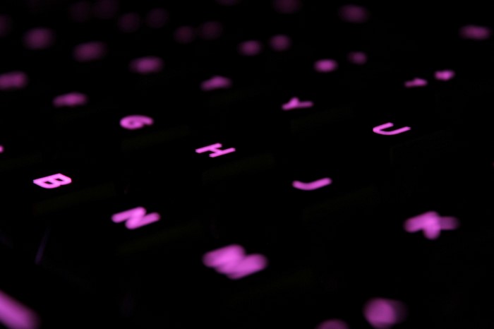 Macro shot of glowing purple keyboard keys in darkness