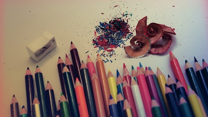 Colored pencils, sharpener, and shavings on a white surface