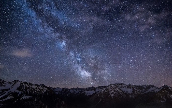 Milky Way galaxy over snow-capped mountains at night