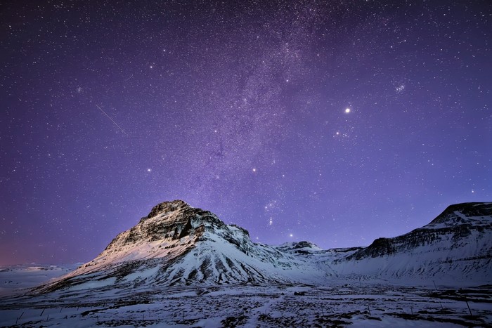 Snowy mountains under a starry night sky